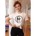 Woman wearing a white t-shirt with a graphic yoga design in a yoga studio setting