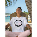 Woman sitting outdoors in Adirondack chair by a beach, wearing a white t-shirt with 'CHILLIN' graphic design.